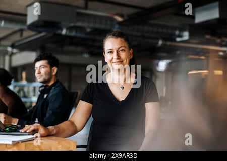 Ritratto di sorridente imprenditrice maturo seduto alla scrivania in ufficio Foto Stock