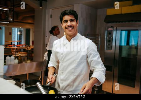 Ritratto di uno chef maschio felice che cucina in cucina commerciale Foto Stock