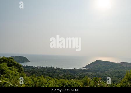 Una tranquilla vista costiera: Il verde lussureggiante incontra le onde scintillanti. L'armonia della natura catturata in pixel. Foto Stock