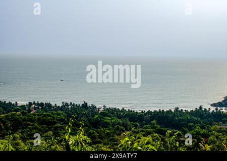 Scopri la serenità in questa scena costiera, dove il verde lussureggiante incontra il mare scintillante. Perfetto per progetti a tema naturalistico. Gokarna Foto Stock