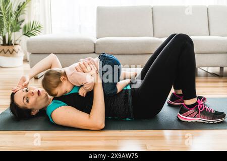 madre stanca che si allena con il bambino il bambino guarda qualcuno. Foto Stock