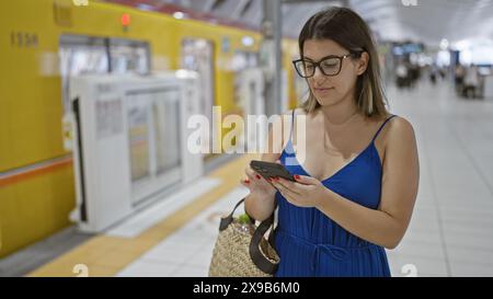 Bellissima donna ispanica con occhiali, al telefono, in attesa del suo viaggio in metropolitana alla stazione di ginza, in mezzo alla vivace vita cittadina Foto Stock