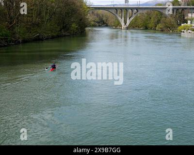 Il kayak solitario pagaia sul fiume Arve verso la confluenza con il Rodano. Quando i fiumi si uniscono, scorrono sotto un viadotto ferroviario, Ginevra, CH. Foto Stock