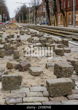 Primo piano di storiche pietre di granito naturale martellate e cesellate a forma di cubo su una pavimentazione stradale incompiuta Foto Stock