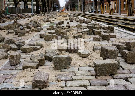 Primo piano di storiche pietre di granito naturale martellate e cesellate a forma di cubo su una pavimentazione stradale incompiuta Foto Stock