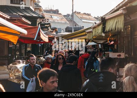 Gli amanti dello shopping curiosano tra i vari stand di Naschmarkt, un mercato all'aperto a Vienna, in Austria, in un soleggiato pomeriggio autunnale Foto Stock