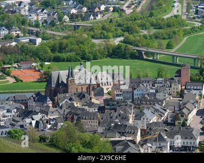 Una città vecchia con una chiesa e molte case, circondata da prati, strade ed edifici rurali, vista dall'alto, piccola cittadina su un fiume tra il verde Foto Stock