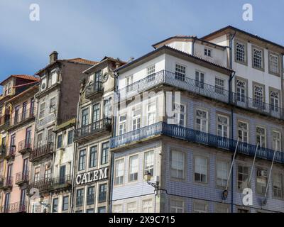 Edifici storici con balconi e facciate elaborate in un quartiere della città vecchia sotto un cielo limpido, case colorate su un fiume con barche colorate Foto Stock