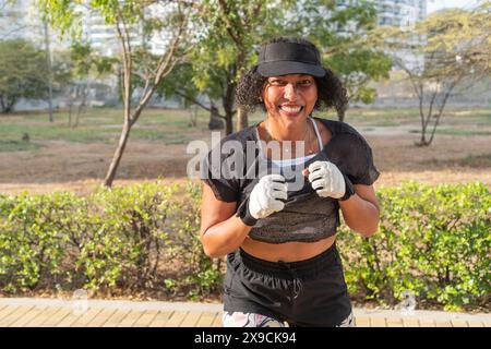 Donna sorridente impegnata in una sessione di allenamento di boxe all'aperto. Foto Stock