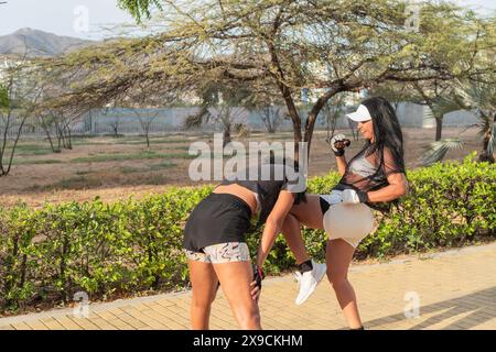 Due donne si sono impegnate in una manovra di colpo al ginocchio durante l'addestramento al combattimento all'aperto. Foto Stock