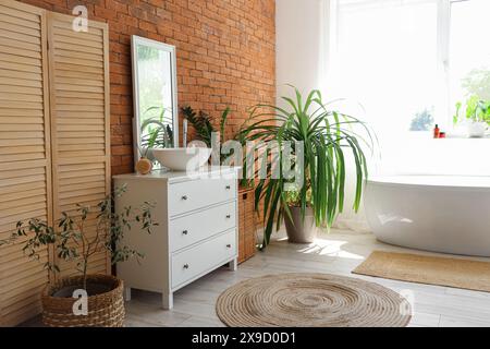 Interno di un elegante bagno con lavandino, comò, specchio, vasca e impianto domestico Foto Stock