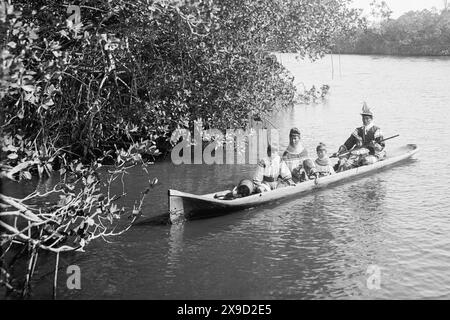 Famiglia indiana Seminole in una canoa scavata su un fiume a Miami, Florida, all'inizio degli anni '1900 (USA) Foto Stock