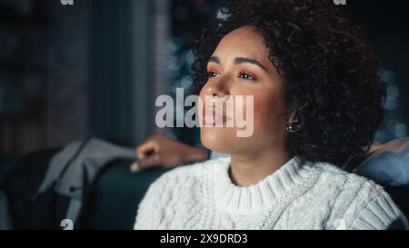 Concentrati sulla donna nera seduta con il marito su un divano e ridendo mentre guardi Comedy TV Show. Persone che riposano insieme sul divano durante il Weekend di notte, godendo di Funny Film. Foto Stock