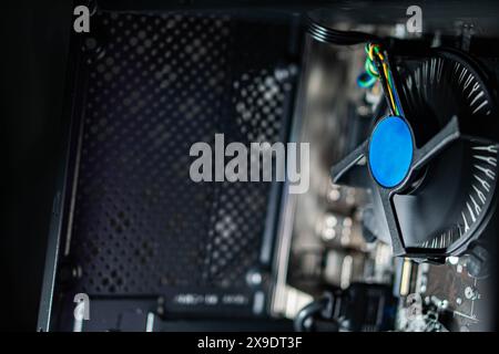 Primo piano di una ventola di raffreddamento del computer all'interno del case di un PC desktop, con cablaggio e componenti visibili. Foto Stock