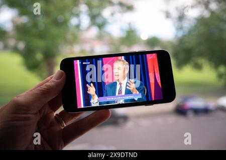 Visto sullo schermo di un iPhone, Nigel Farage risponde a una domanda sull'immigrazione durante la trasmissione in diretta di BBC TV Question Time nella prima settimana della campagna elettorale del 2024, il 30 maggio 2024, a Londra, Inghilterra. Foto Stock