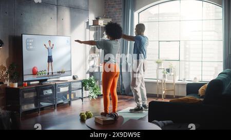 Athletic Black Couple Training Together, Jumping, dopo l'esercizio video online di Professional Trainer in TV nella Bright Room di casa. Fidanzato felice e fidanzata si allenano insieme. Foto Stock
