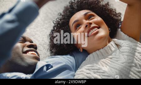 Espressione amore e tenerezza: Coppia afroamericana che si posa per terra e gode di relazioni. Il giovane fidanzato e la fidanzata ridono e giocano con le mani a casa. Foto Stock