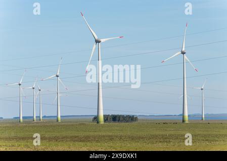 Un campo di turbine eoliche con un cielo azzurro chiaro sullo sfondo Foto Stock