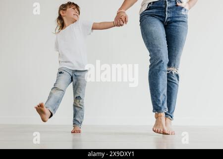 Madre e figlia si tengono per mano mentre camminano verso la telecamera Foto Stock