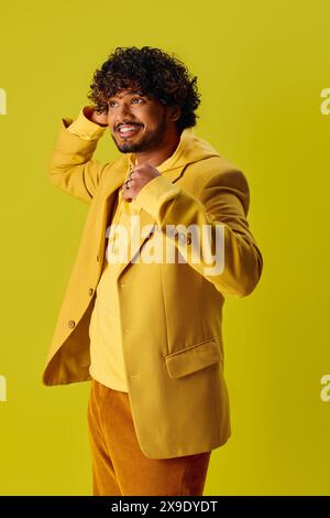 Bell'uomo indiano con giacca gialla e pantaloni marroni in posa su uno sfondo vivace. Foto Stock