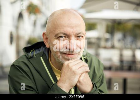 Uomo anziano con barba che riposa Chin a portata di mano in un ambiente urbano all'aperto Foto Stock