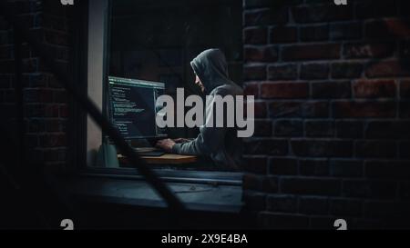 Appartamento notturno: Malvagio hacker con cappuccio irrompe nella sala server dati, attacco DDOS, schema di phishing, malware. Darknet Cyber Crime. Vista dall'esterno verso la finestra. Foto Stock