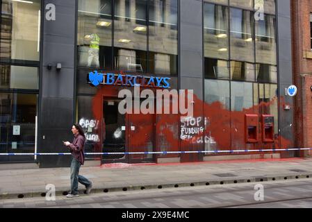 Barclays Bank, Mosley Street, centro di Manchester, Regno Unito, una porta di vetro si è rotta e coperta di vernice rossa il 31 maggio 2024. La polizia ha messo in atto un cordone. Negli ultimi mesi i manifestanti pro-Palestina hanno preso di mira questa banca e gettato vernice rossa ad altre imprese che credono stiano sostenendo Israele. I graffiti sul fronte includono: "Smettete di finanziare il genocidio”. Foto Stock