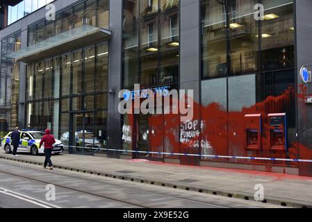 Barclays Bank, Mosley Street, centro di Manchester, Regno Unito, una porta di vetro si è rotta e coperta di vernice rossa il 31 maggio 2024. La polizia ha messo in atto un cordone. Negli ultimi mesi i manifestanti pro-Palestina hanno preso di mira questa banca e gettato vernice rossa ad altre imprese che credono stiano sostenendo Israele. I graffiti sul fronte includono: "Smettete di finanziare il genocidio”. Foto Stock