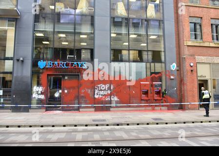 Barclays Bank, Mosley Street, centro di Manchester, Regno Unito, una porta di vetro si è rotta e coperta di vernice rossa il 31 maggio 2024. La polizia ha messo in atto un cordone. Negli ultimi mesi i manifestanti pro-Palestina hanno preso di mira questa banca e gettato vernice rossa ad altre imprese che credono stiano sostenendo Israele. I graffiti sul fronte includono: "Smettete di finanziare il genocidio”. Foto Stock