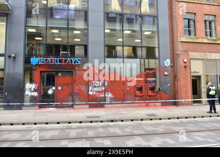 Barclays Bank, Mosley Street, centro di Manchester, Regno Unito, una porta di vetro si è rotta e coperta di vernice rossa il 31 maggio 2024. La polizia ha messo in atto un cordone. Negli ultimi mesi i manifestanti pro-Palestina hanno preso di mira questa banca e gettato vernice rossa ad altre imprese che credono stiano sostenendo Israele. I graffiti sul fronte includono: "Smettete di finanziare il genocidio”. Foto Stock