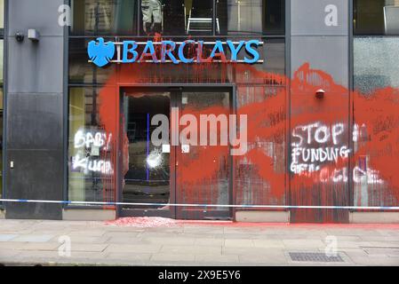 Barclays Bank, Mosley Street, centro di Manchester, Regno Unito, una porta di vetro si è rotta e coperta di vernice rossa il 31 maggio 2024. La polizia ha messo in atto un cordone. Negli ultimi mesi i manifestanti pro-Palestina hanno preso di mira questa banca e gettato vernice rossa ad altre imprese che credono stiano sostenendo Israele. I graffiti sul fronte includono: "Smettete di finanziare il genocidio”. Foto Stock