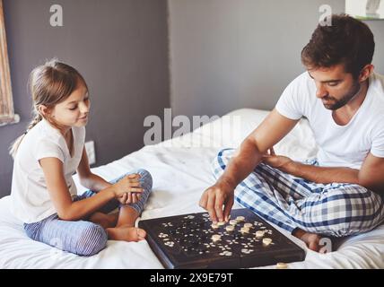 Giocare, ragazza e papà con le dama a casa per insegnare, strategia e apprendimento per lo sviluppo delle abilità. Camera da letto, padre e figlia con gioco da tavolo Foto Stock