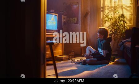 Young Boy che gioca a Eighties Eight bit Arcade Video Game su una console a casa nella sua stanza con interni Old-School. Il bambino vince con successo il livello. Nostalgico concetto d'infanzia retrò. Foto Stock