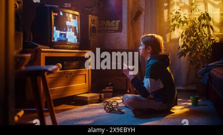 Young Boy che gioca a Eighties Eight bit Arcade Video Game su una console a casa nella sua stanza con interni Old-School. Il bambino vince con successo il livello. Nostalgico concetto di infanzia. Foto Stock