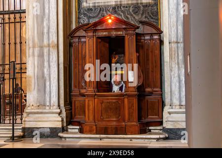 Un sacerdote seduto in una cassetta di confessione all'interno della Basilica di Santa Maria maggiore, una delle quattro Basiliche Papali a Roma, Italia. Foto Stock