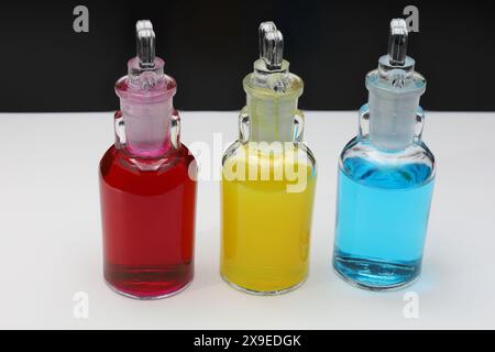 STILL Life con tre piccoli flaconi riempiti di liquidi colorati su sfondo bianco e nero. Foto Stock