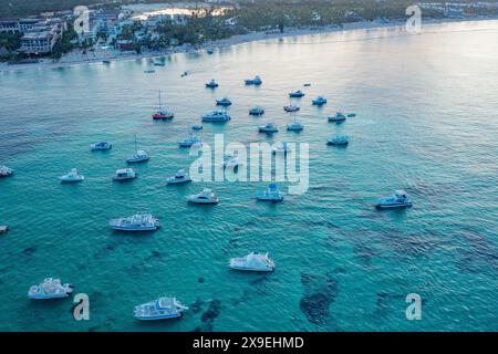 Vista aerea sulla spiaggia tropicale atlantica con ombrelloni di paglia, palme e barche. Punta Cana, Dominicana Foto Stock