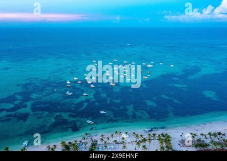 Vista aerea sulla spiaggia tropicale atlantica con ombrelloni di paglia, palme e barche. Punta Cana, Dominicana Foto Stock