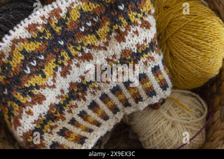Foto ravvicinata del tradizionale cappello a maglia di lana di Fair Isle in corso sugli aghi con palle di filato Foto Stock