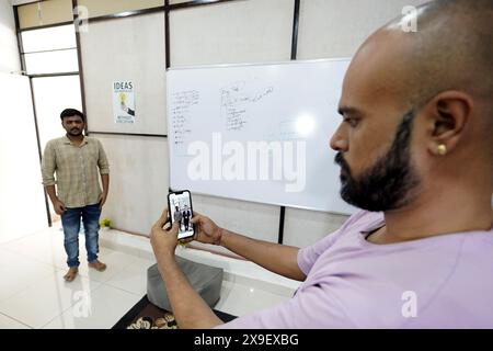 Ajmer, India. 15 maggio 2024. Divyendra Singh Jadoun, proprietaria di Polymath Synthetic Media Solutions, dimostra con un collega come le persone possono scattare selfie con gli avatar dei politici nel loro ambiente familiare. Tra le altre cose, l'azienda crea video falsi per le campagne elettorali. Crediti: Himanshu Sharma/dpa/Alamy Live News Foto Stock