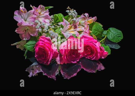 Splendide rose vivaci e fiori rosa e bianchi su una superficie nera lucida riflettente Foto Stock