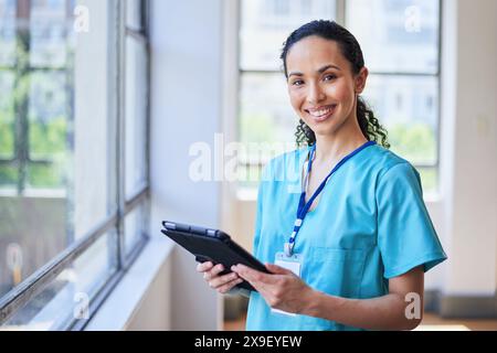 Infermiera sorridente con tablet in un ambiente ospedaliero Foto Stock
