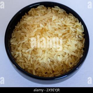 Zenithal fot di una ciotola con riso giallo parboiled su sfondo bianco. Foto Stock
