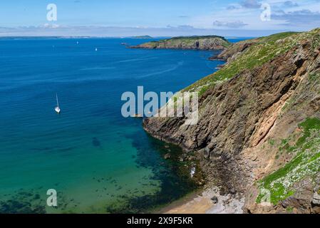 Affacciato sulla spiaggia di Grand Greve con yacht bianco ormeggiato dal ponte di la Coupee che collega Big alle isole del Canale di Little Sark in un incantevole giorno di maggio di sole Foto Stock