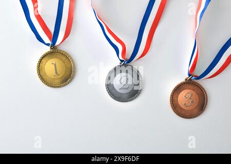 Set di medaglie da competizione sportive in metallo con numeri di posizione incisi su sfondo bianco. Vista dall'alto. Foto Stock