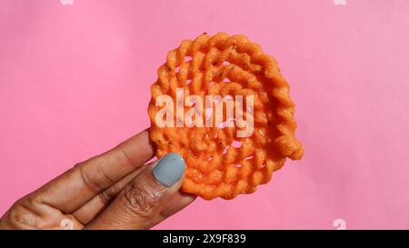 Tè tradizionale indiano snack chakli o Murukku in mano Foto Stock