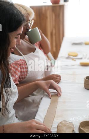 Verticale di due diverse donne in un laboratorio di ceramica e che producono tazze di argilla. Foto Stock