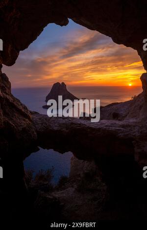 Vista dell'isolotto di es Vedra attraverso la grotta rocciosa al tramonto, Sant Josep de sa Talaia, Ibiza, Isole Baleari, Spagna Foto Stock