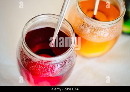 Primo piano di due vasetti di vetro riempiti con colorante multicolore per far morire le uova di Pasqua Foto Stock