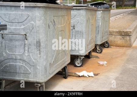 Tre contenitori di rifiuti su ruote con sporcizia lasciati senza scrupoli davanti a loro. Foto Stock